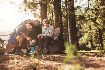 Happy campers making coffee in the wilderness - obrazy, fototapety, plakaty