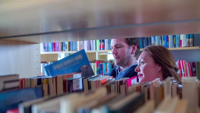 Couple is searching books in library