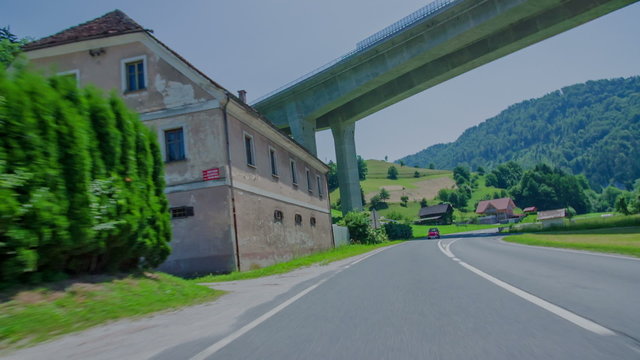 Small red vintage car passing a farm