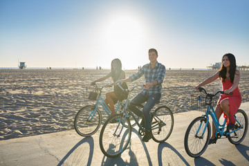 happy friend bicycling together on sunny summer beach in california usa - Powered by Adobe