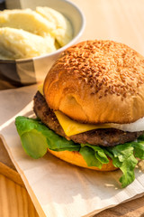 Yummy Beef and cheese Hamburger place on wood tray beside Potato