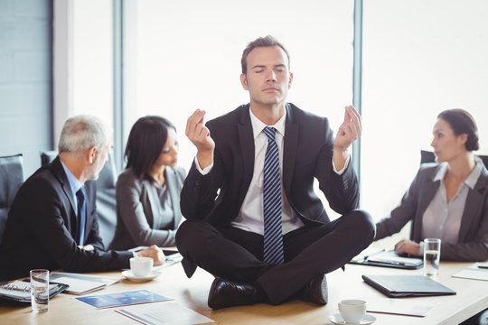 Businessman meditating in conference room