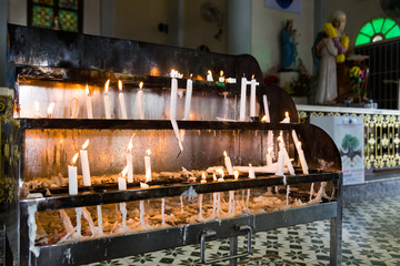 Candles station with burning candles within Catholic church
