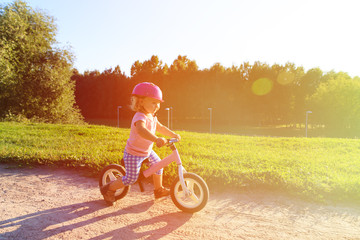 little girl with helmet riding bike at sunset