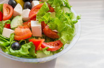 Greek salad with vegetables, cheese and olives in plastic container. Selective focus.