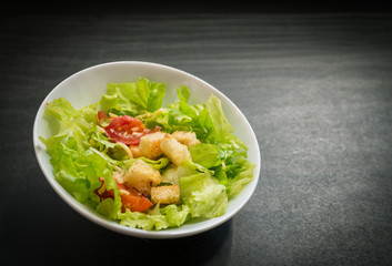 Caesar salad made of fresh vegetables on dark background. Selective focus.