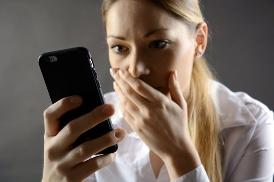 Frau mit Smartphone hat Schock wegen Mobbing, Trauerfall oder Nachricht