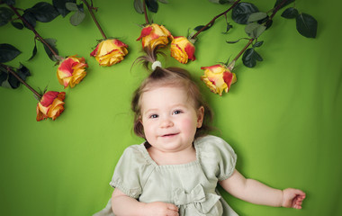 Fototapeta na wymiar pretty little girl lying on green blanket with yellow roses