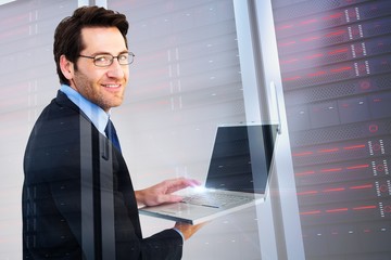 Composite image of smiling businessman using a laptop 
