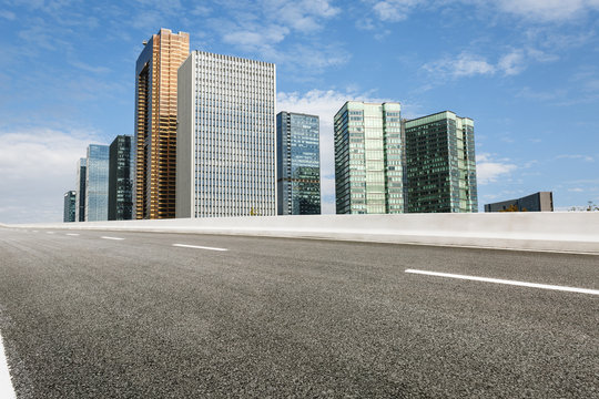 Fototapeta The modern urban commercial building and asphalt road