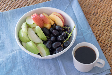 Bowl of fresh fruits with coffee on top of rattan furniture