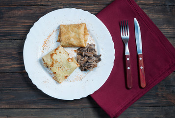 Pancakes pancakes with mushrooms and onions on a white plate