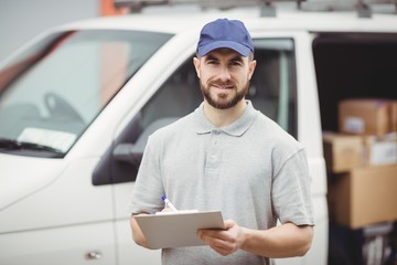 Delivery man writing on clipboard