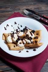 pancakes with chocolate and banana on a wooden background