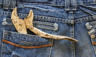 Wrench locked in a blue jeans pocket,concept for labors day and fathers day background.