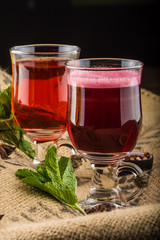 Cups of drinks with cinnamon sticks and stars anise, mint leaves and sliced fruits
