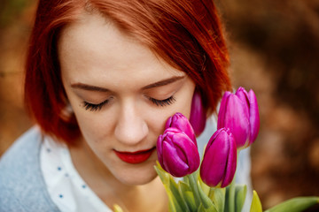 Fototapeta premium Young woman with a bouquet of tulips at the park in early spring