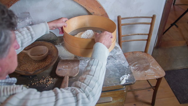 Sieving the fresh slower in the wooden strainer 