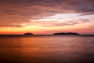 Naklejka na ściany i meble Sunset with dramatic clouds on the tropical beach while magic hour.