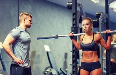 man and woman with barbell flexing muscles in gym