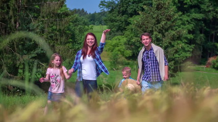 Family is walking near wheat field and waving to the farmer
