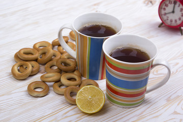Two cups for tea with fragrant bagels on  wooden background
