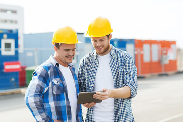 two smiling builders in hardhats with tablet pc
