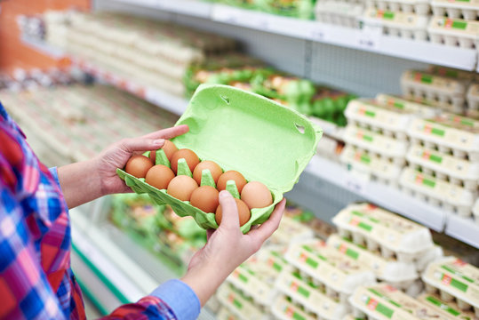 In hands of woman packing eggs in supermarket