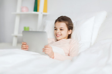 happy girl lying in bed with tablet pc at home