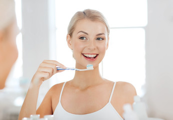 woman with toothbrush cleaning teeth at bathroom