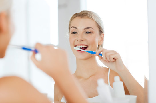 Woman With Toothbrush Cleaning Teeth At Bathroom