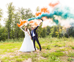 Wedding couple with color smoke in the summer park.