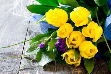 Bouquet of yellow tulips in a gift on a dark wooden table
