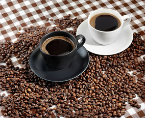  Two coffee cups and coffee beans on a checkered cloth