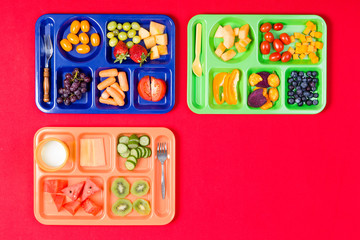 Three kids lunch trays with fruit