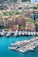 Fototapeta na wymiar Cityscape with luxury yachts in harbour of Monaco, Cote d'Azur