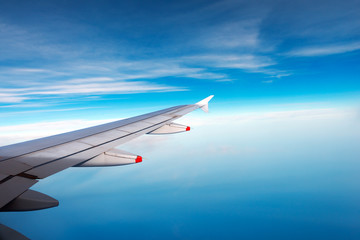Wing of a Plane with Blue Sky and Clouds / Wing of a plane over the blue sea with blue sky and...