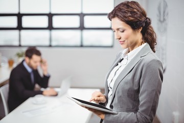 Businesswoman using tablet while colleague in background