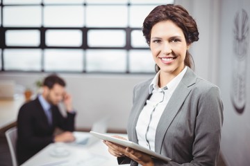 Businesswoman using tablet  while colleague in background