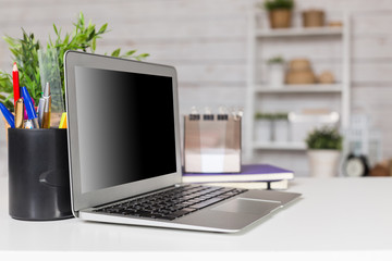 Laptop with blank screen on table in office room