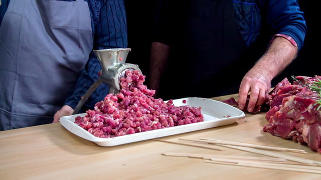 Two adults grinding meat