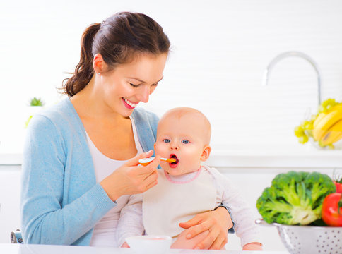 Mother Feeding Her Baby Girl With A Spoon