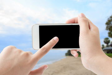 Concept of Woman hand touching smartphone in beach