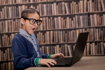 surprised young  boy in the library with computer