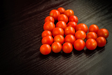 Cherry tomatoes in a heart shape on a black background