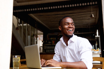 Smiling black businessman working on laptop at cafe