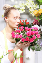 Kwiaciarnia, kobieta wącha różowe róże.