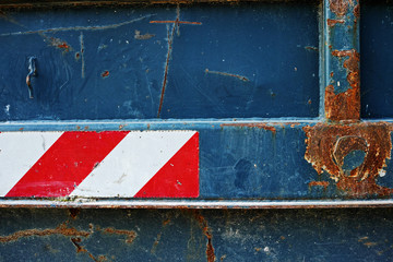 Warning tape.Close-up view of do not cross red and white tape on rusty metal container. Background image detail.
