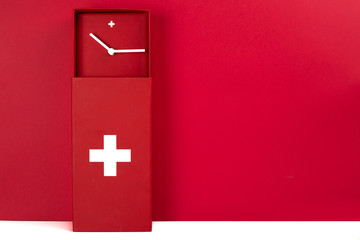 Une pendule moderne rouge et blanche aux couleurs du drapeau suisse, sur fond rouge et blanc