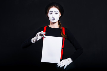 Girl mime holding white sheet of paper/Woman mime with white face holding a sheet of white paper on black background